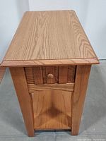 Side angle showing full table height with drawer and bottom shelf, wood grain and drawer operation.