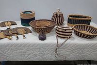 Wide view of the lot showing handwoven baskets, fans, and bag arranged on a white surface