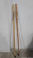 Pair of two natural solid wood walking sticks side by side, showing full length and variation in wood tone and grain.