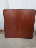 Top view of the Stakmore square cherry wood folding table with straight edges and smooth polished surface.