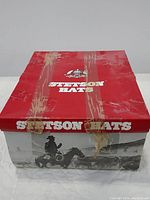 Red and white Stetson branded cardboard hat box with signs of wear and tape residue