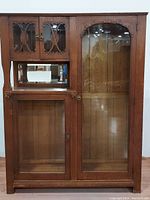 Full cabinet front view showing side by side configuration: left side with smaller upper doors and larger lower door, right side with tall glass door with carved arch.