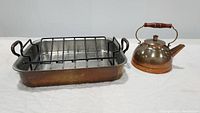 Photo showing the copper roasting pan with rack and the copper tea pot together on a white surface.