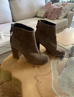 Side and front views of Steve Madden brown suede ankle boots with block heels on wooden table.