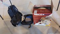 Nesco Food Dehydrator Box with two lunch bags and a small backpack with bistro set on floor.