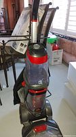 Full upright view of Bissell Revolution Pet carpet cleaner showing red and black body with clear tanks and handle.