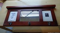 Full front view of the wooden frame with mirror and three coat hooks showing overall condition and design.