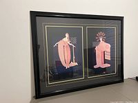 Framed two vintage Erte art deco prints with black and gold matting in a wood frame.