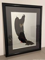 Full view of framed art piece leaning against wall, showing overall composition of figure, mat and frame.