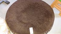 Top side view of the round dog bed showing brown plush fabric and a size tag marked 40 inch diameter.