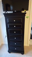 Front view of black six-drawer lingerie chest with TV on top