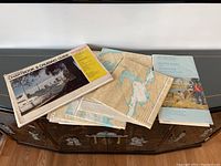 Lot contents showing the chartbook, folded maps, and guidebook arranged on a cabinet.