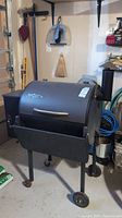 Full view of black Traeger grill on wheels in garage