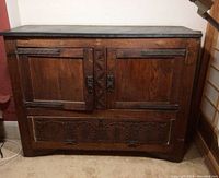 Front view of cabinet showing dual doors, carved lower panel and granite top