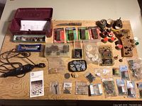 Full overview of Dremel tool and accessories laid out on a wooden surface including tool, storage box, and multiple small bags of attachments.