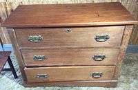 Solid wood dresser with three drawers and brass handles, front view