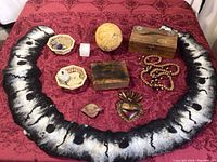 Full view of lot showing felted wool pieces, wooden boxes, metal heart wall hanging, shells, beach glass, stone cube and beaded necklaces on red textured fabric.