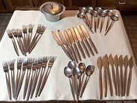 Wide shot of cutlery set and small pot arranged on tablecloth