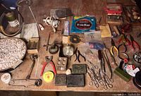 Photo showing wide variety of jewelry making tools including pliers, hammer, metal stamping pieces, and metal shaping tools on a wood table.