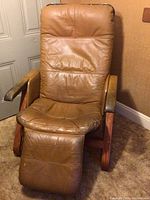 Front view of the leather and wood recliner chair showing tan leather upholstery and extended footrest.