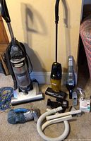 Full view of all vacuums and accessories on carpet showing relative size and type.