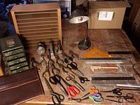 Full view of lot showing leather portfolio, wooden paper shelf, metal drawers, lamp, hole punchers, stampers, scissors, rulers and other office supplies.