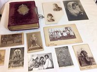 Photo showing the purple velvet photo album with brass nameplate and assorted vintage photographic prints laid out next to it.