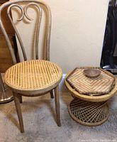 Wood chair with cane woven seat next to a round bamboo stool with hexagonal detailing on top and a small wooden bowl on the stool