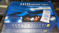 Top view of the HID Xenon Light box showing branding and car headlights graphics.