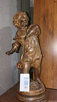 Full front view of the Pebble Thrower collectible statue showing child's detailed face, flowing dress and dynamic throwing pose with rounded base.