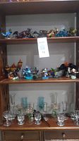 Shelf display of mixed Skylanders figures and various small wine glasses below