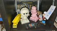 Display of various antique items including figurines, toy vehicles, and a license plate on a shelf.
