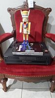 Sony DVD player with remote control and a wooden nutcracker figurine on top, all placed on the red chair