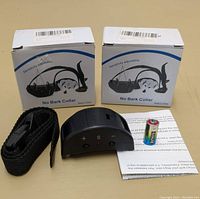 Two boxed no bark collars shown with accessories including strap, small battery, and instruction sheet on a beige surface.