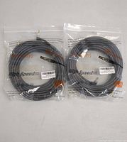 Two gray and black braided stereo audio cables in sealed plastic bags, each with a right-angle 3.5mm audio connector visible.