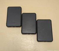 Front view of three black portable power banks placed side by side showing LED indicators and compact design.