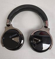 Top view of black Cowin Bluetooth headphones showing padded headband and glossy ear cups with logo and controls