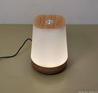 Front angle showing the mini night lamp illuminated, with visible wooden top, white shade, and black power cable.