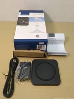 Insignia Qi wireless charging pad, power adapter, USB cable, instruction manual, and box shown from front.