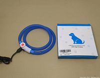 Full view of the blue USB rechargeable LED pet collar and the white and blue packaging with dog illustration.