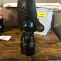 Side view of the hand carved African bust sculpture showing profile and details of headdress and braided hair.