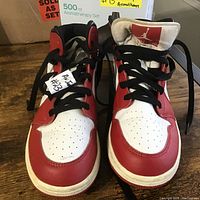 Front view of the pair of Air Jordan 1 Retro High OG sneakers in Chicago colorway, red, white, and black, showing perforated toe box and black laces.