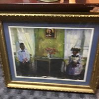 Framed signed painting of a boy and girl sitting in an interior with floral centerpiece on table and portrait on wall