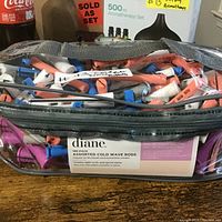 Clear zippered bag filled with assorted colored cold wave rods lying on a wooden surface; Diane brand label visible showing 160-pack.