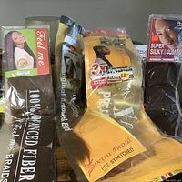 Lot of synthetic braiding hair bundles in packaging showing various brands and color shades.