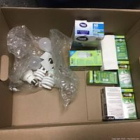 Photo of assorted light bulbs including unpackaged spiral CFL bulbs and boxed bulbs from Niagara and Great Value brands.