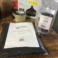 Lot with Diane neck duster in packaging, Empire Pro Zipper Jacket in packaging, and other unrelated items partially visible.
