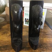 Front view of the pair of hand carved African wooden carvings mounted on rectangular plaques showing detailed face profiles and carved hairstyles.