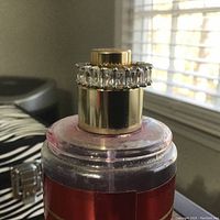 Close-up photo of the ring placed on a gold and red perfume bottle cap to show the stone details and band finish.