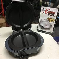 GT Xpress 101 snack maker with lid open, showing divided cooking plates and original box featuring product image and serving suggestion.